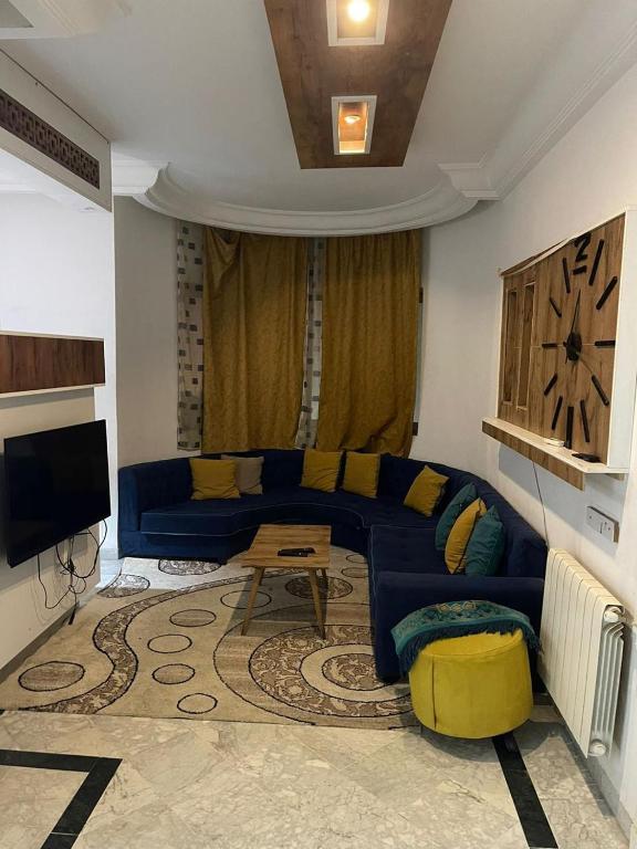 a living room with a blue couch and a tv at Studio in Ariana