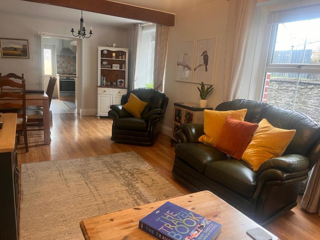 a living room with two leather chairs and a table at Kookaburra Cottage in Brecon