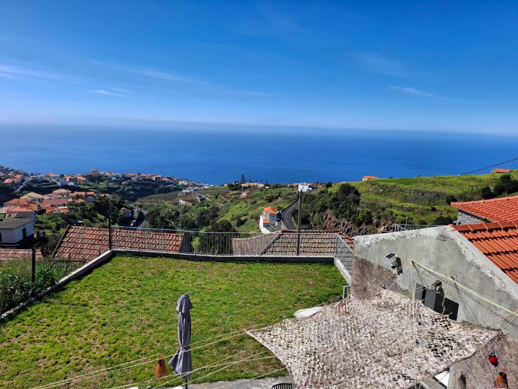 a view of a field of grass with the ocean in the background at Casa Rosinha, views & sunset in Calheta
