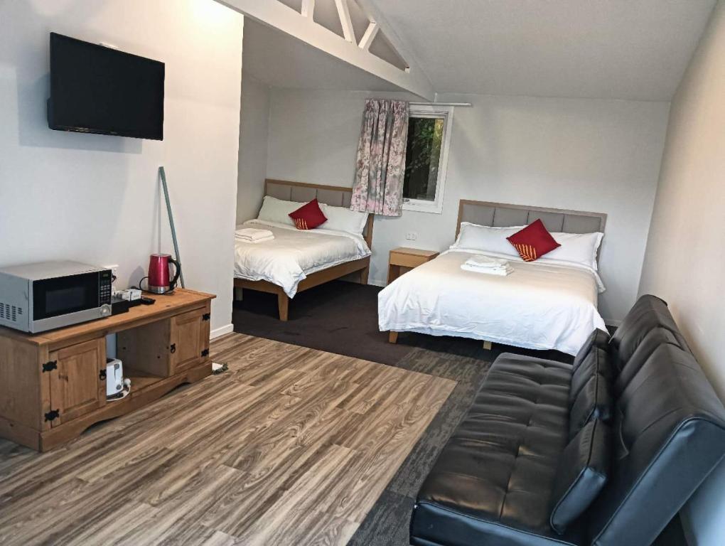 a hotel room with two beds and a couch at 2 double and 1 sofa beds Chalet D in Rotorua