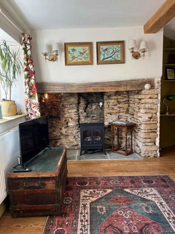 a living room with a stone fireplace and a table at Matchbox Cottage in Frome