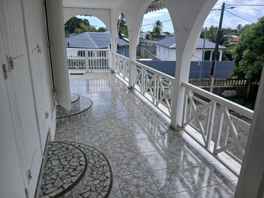 a balcony with a white railing and a walk way at Haut de Villa Manguier in Petit-Bourg
