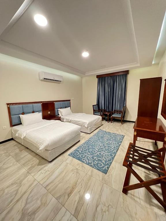 a bedroom with two beds and a desk and a piano at كاسا للشقق المخدومة 2 in Dammam
