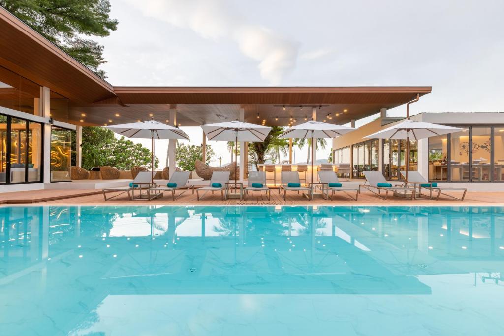 a pool at a hotel with chairs and umbrellas at LIV Hotel Phuket Patong Beachfront in Patong Beach