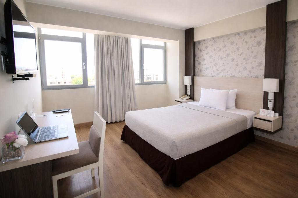 a hotel room with a bed and a desk with a laptop at Palmetto Hotel Business San Miguel in Lima