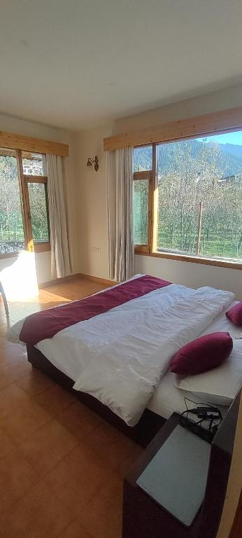 a large bed in a bedroom with a large window at Peaceful huts in Manāli