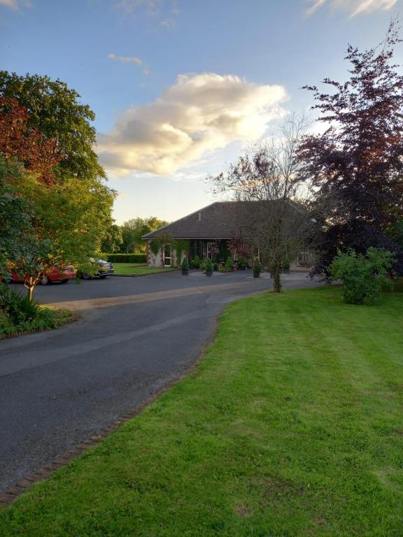 a house with a road in front of a yard at The Hermitage Riverside House in Clogheen
