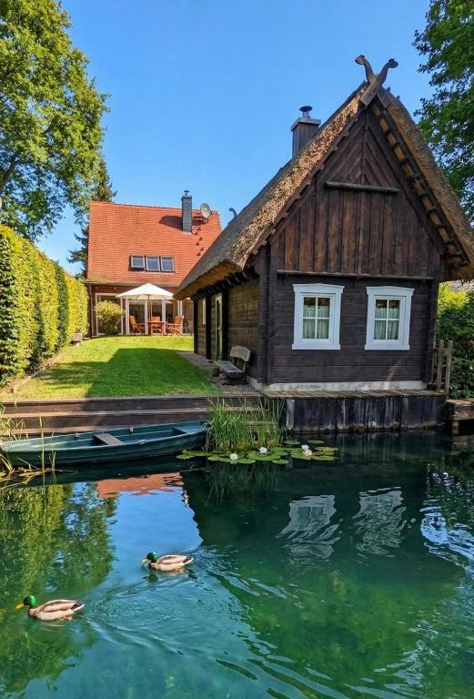 a house with a pond in front of it at Ferienhaus Fließ Paradies mit privatem Saunahaus - Leipe, Spreewald in Leipe
