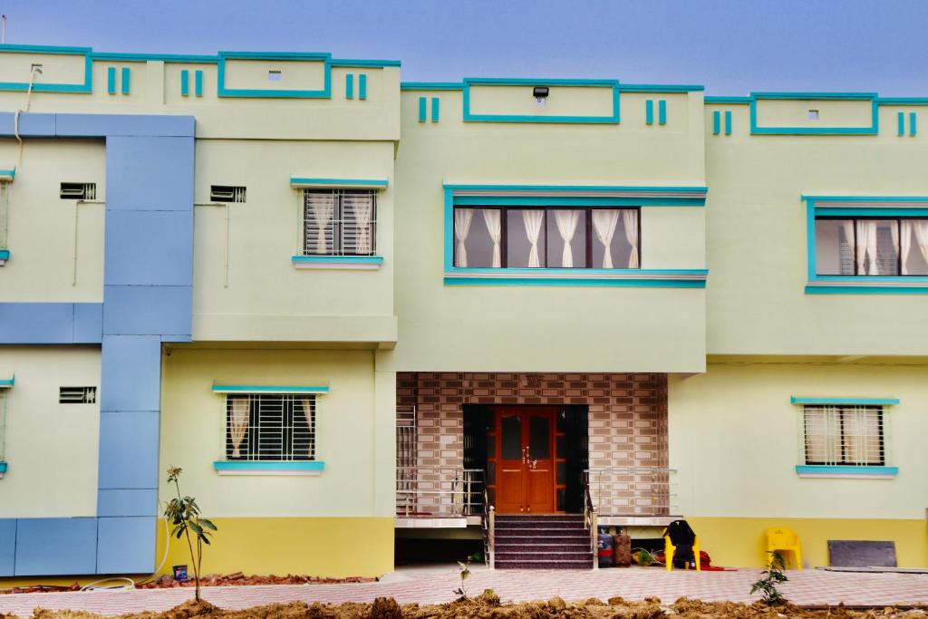 a large white building with a red door at Sky View Guest House in Shānti Niketan
