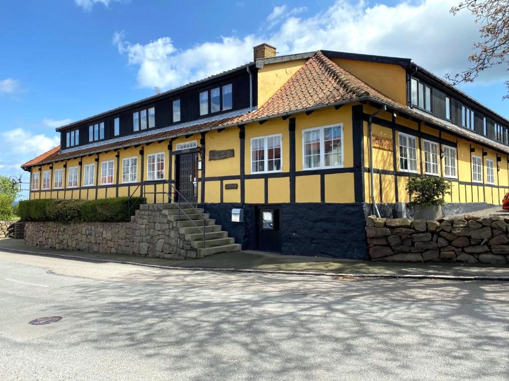 a yellow and black house with a stone wall at Hotel Villum in Sandvig