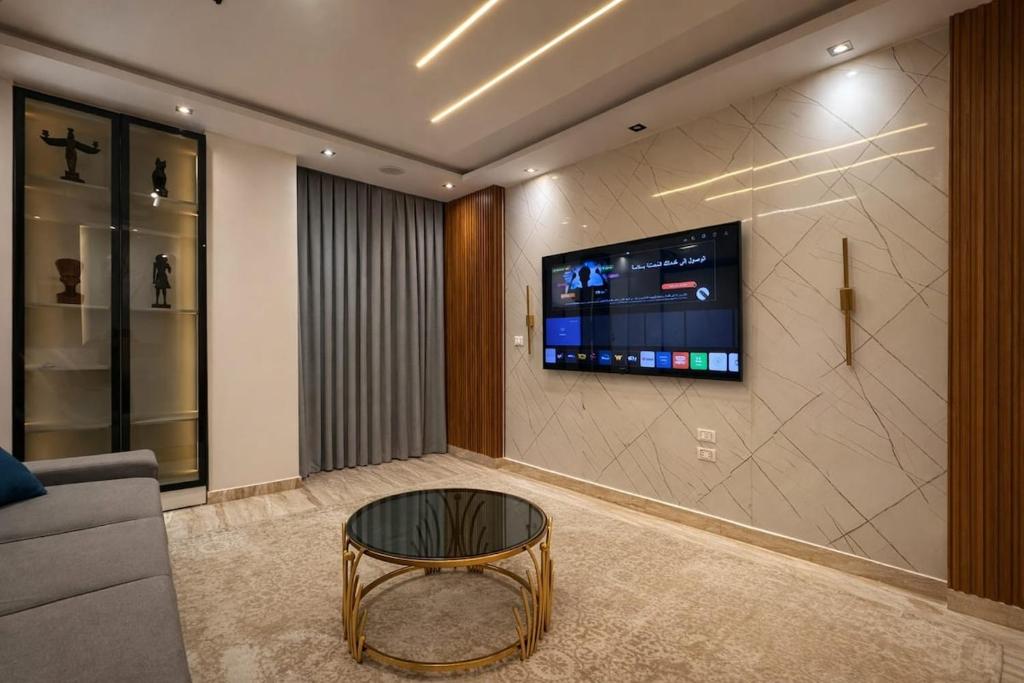 a living room with a couch and a tv on a wall at Cabilyt Cairo Luxiury Apartment in Obour