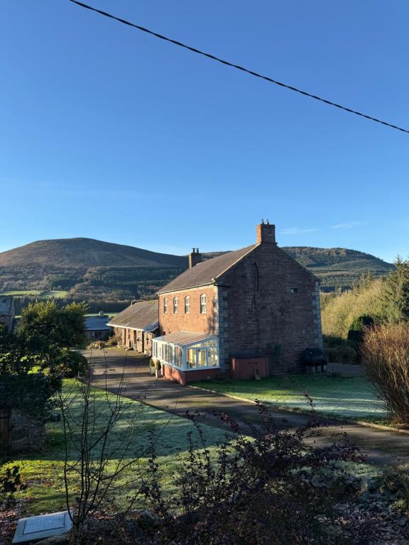 an old building in a field with hills in the background at Castle Oliver Farm in Ardpatrick