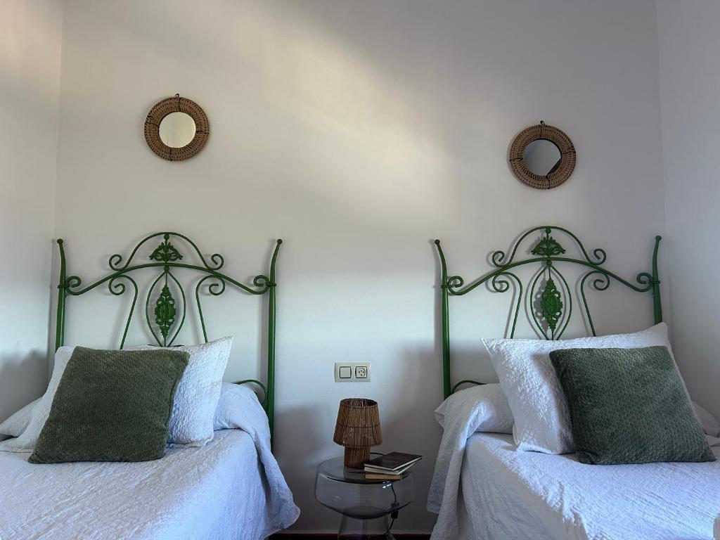 two beds in a bedroom with two mirrors on the wall at Casita El Granero in Iznatoraf