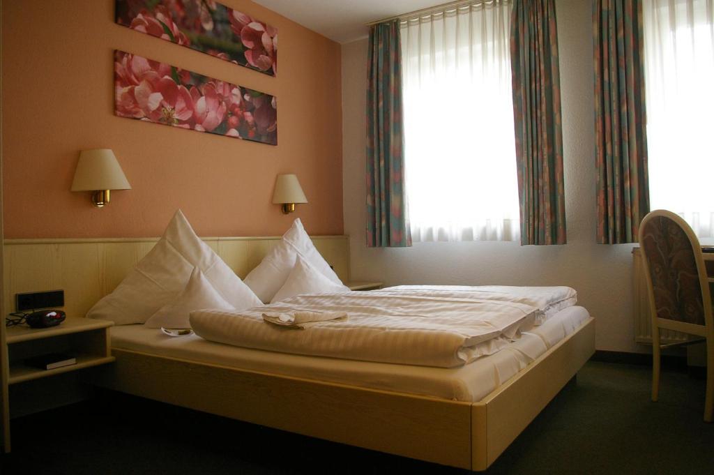 una habitación de hotel con una cama con sábanas blancas y una ventana en Zum treuen Bartel, en Markgröningen
