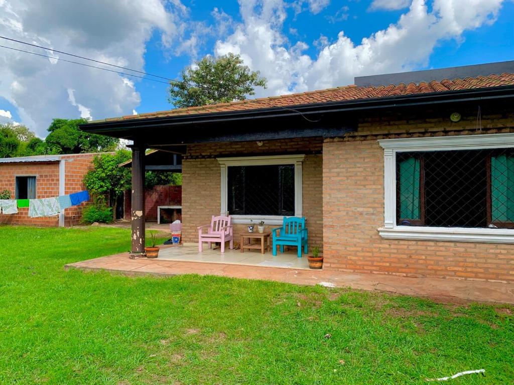a house with a patio with two chairs and a table at The Mango House in Caaguazú