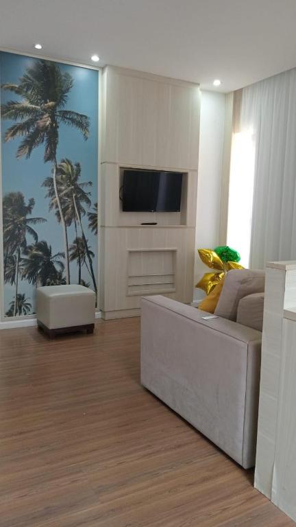 a living room with a white couch and a tv at Flat colado a praia de Boa Viagem in Recife