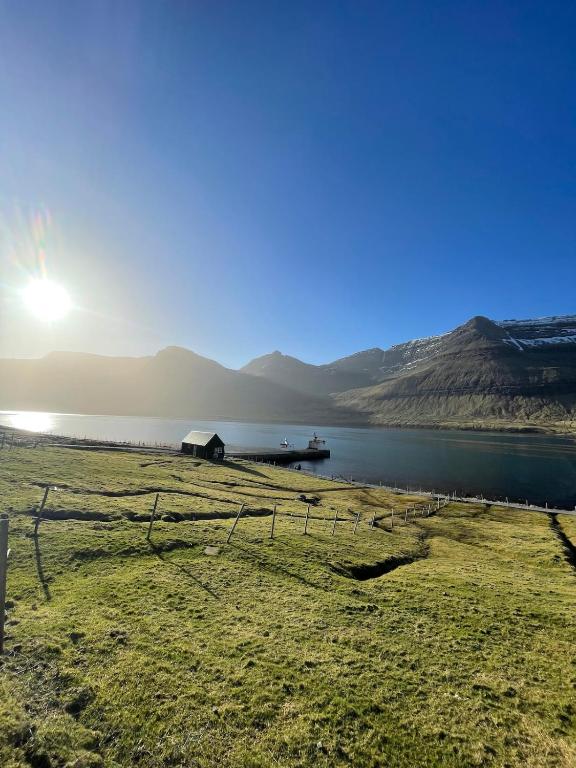 a fence next to a body of water with a dock at FjordNest Cabin in Hvannasund