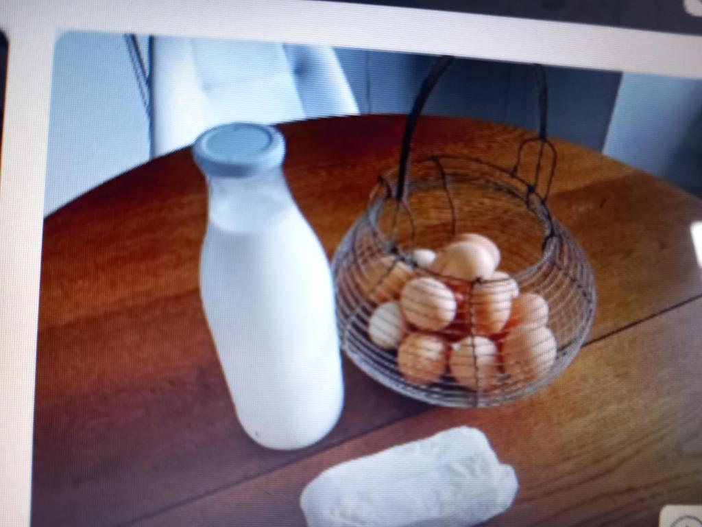 a bottle of milk and a basket of eggs on a table at A la ferme chez Christian in Escaudoeuvres