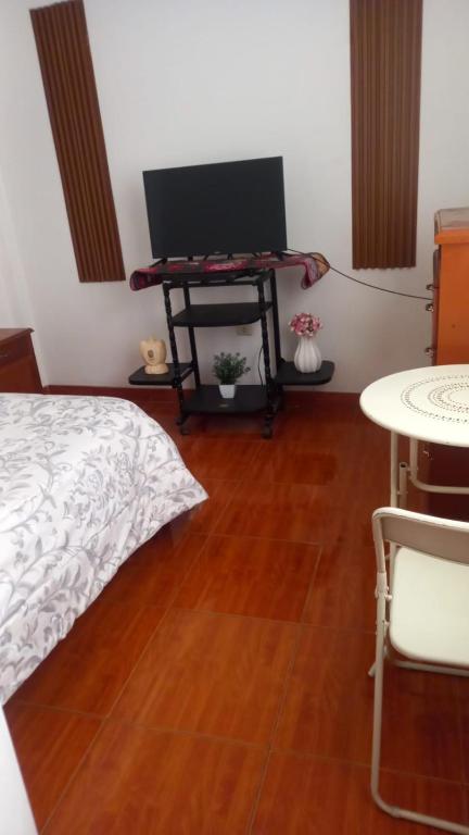 a bedroom with a bed and a table with a tv at Habitación Privada Centro in Ayacucho