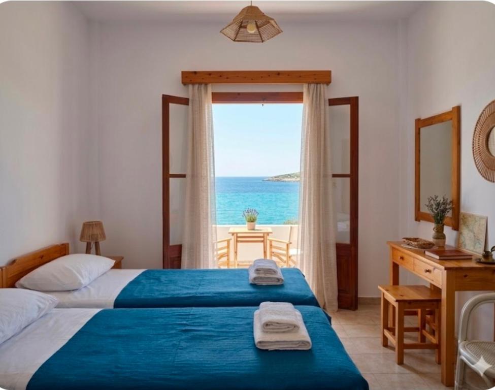 a bedroom with a bed and a window with the ocean at Louis Studios and Apartments Melitsaha Beach in Kalymnos