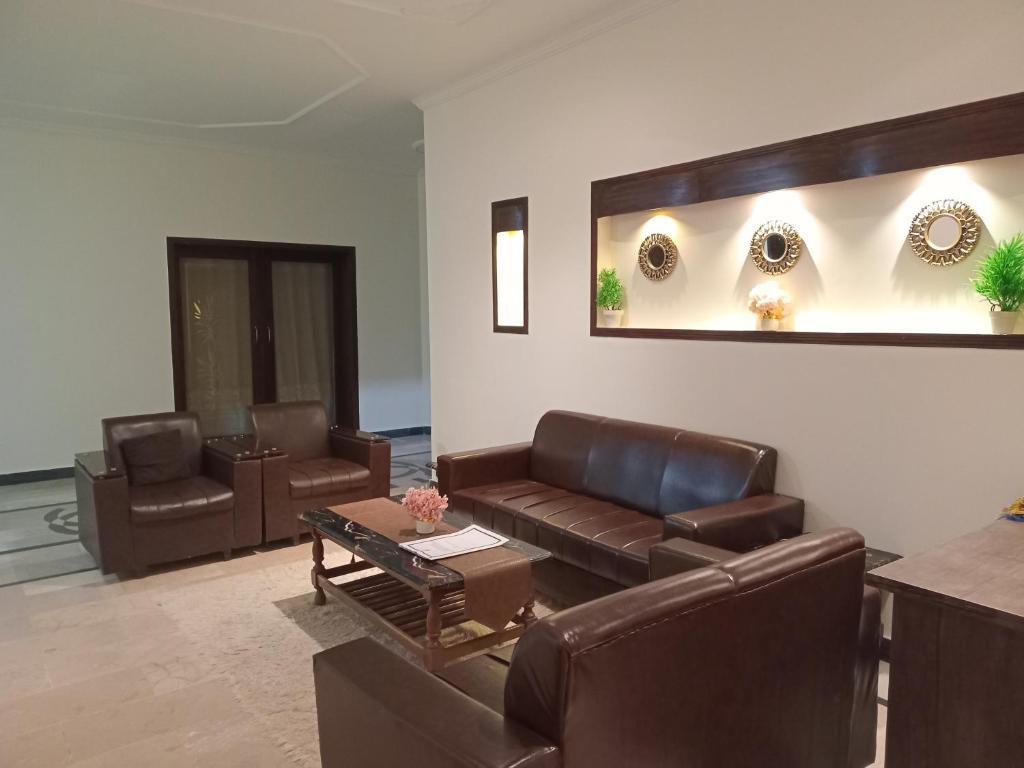 a living room with leather couches and a table at The Velmora G-13 in Islamabad