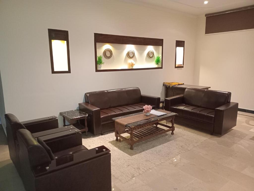 a living room with leather couches and a table at The Norvane G-13 in Islamabad