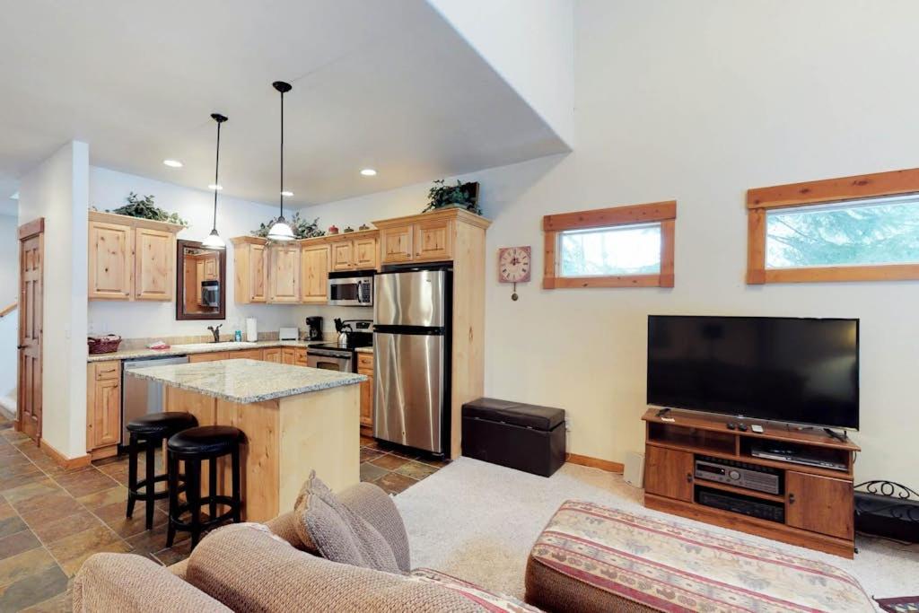 a living room with a kitchen with a large television at McCall Golf Condo - Pool Courts & Patio in McCall