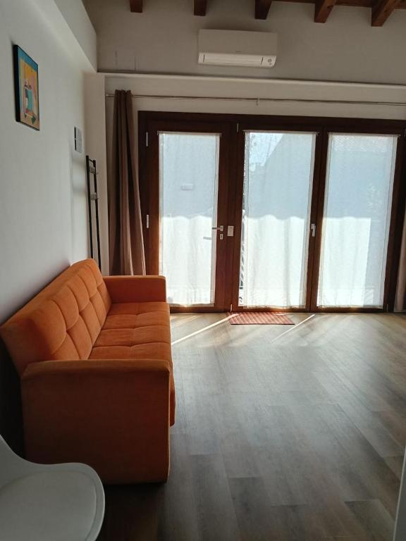 a living room with an orange couch and large windows at NaturalmenteLucia in Cologno al Serio