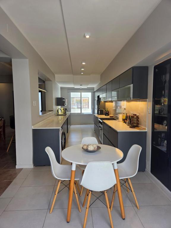 a kitchen with a table and white chairs at Espectacular Casa con pileta y jacuzzi in San Juan