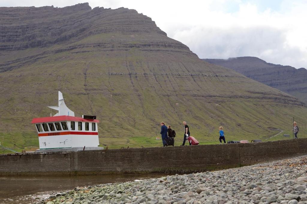 a group of people standing on a wall near a lighthouse at Captains Room - Havborg in Hvannasund