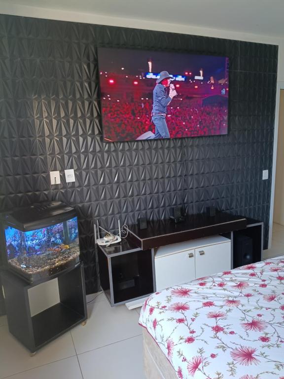 a room with a tv on a wall with a bed at Casa com Piscina e Ar Condicionado in Imbé