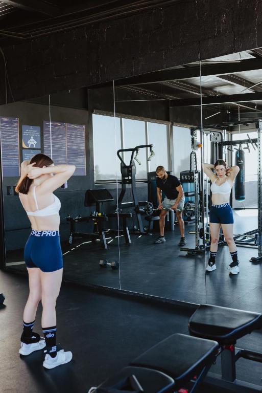 A bright, mirrored gym with people using cardio and strength equipment.