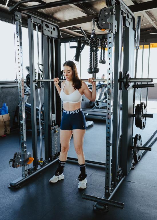 A strength-training station occupies the centre of a bright gym.