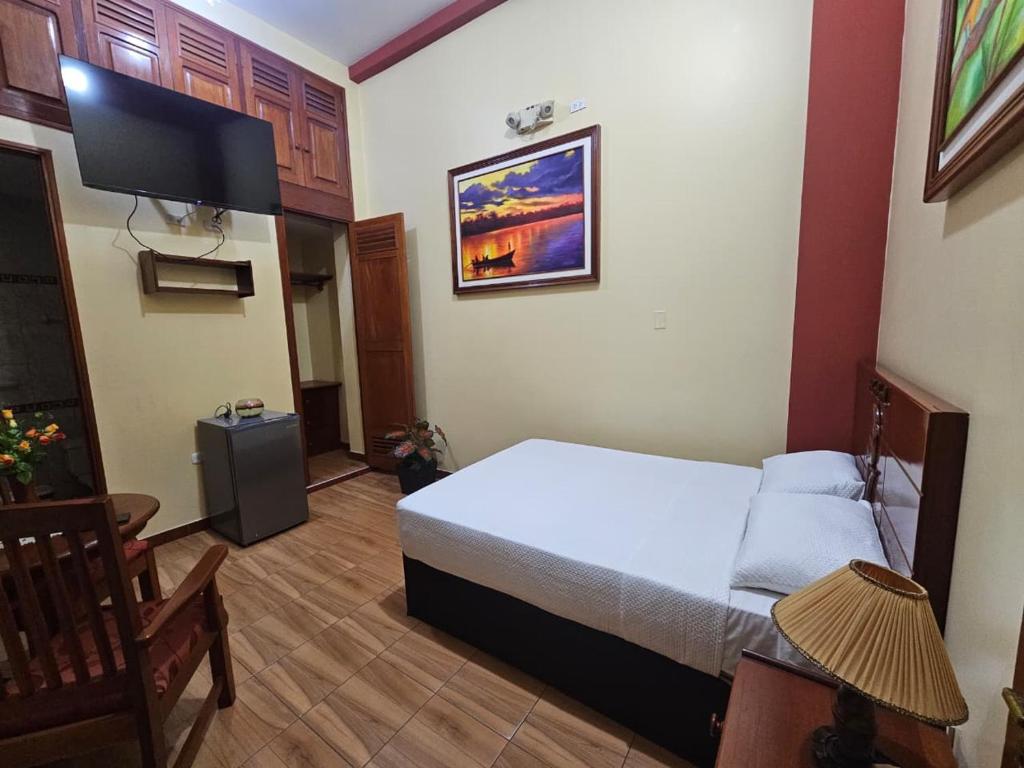 a bedroom with a bed and a flat screen tv at Alojamiento El Cardenal in Iquitos