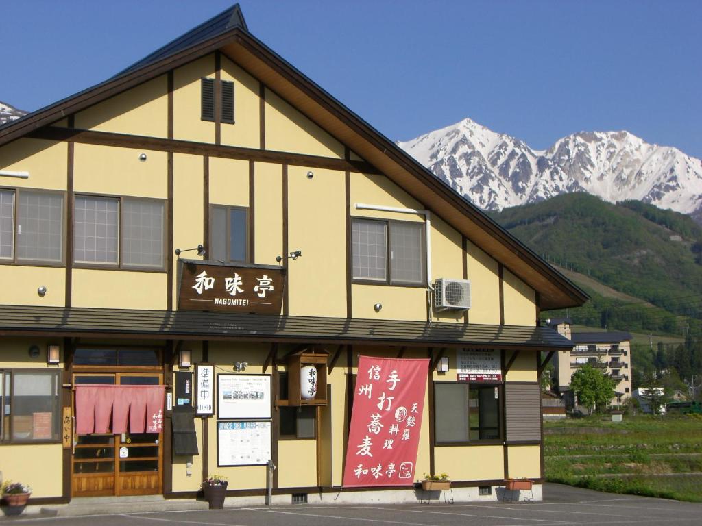 a building with chinese writing on it with mountains in the background at Nagomi-tei in Hakuba
