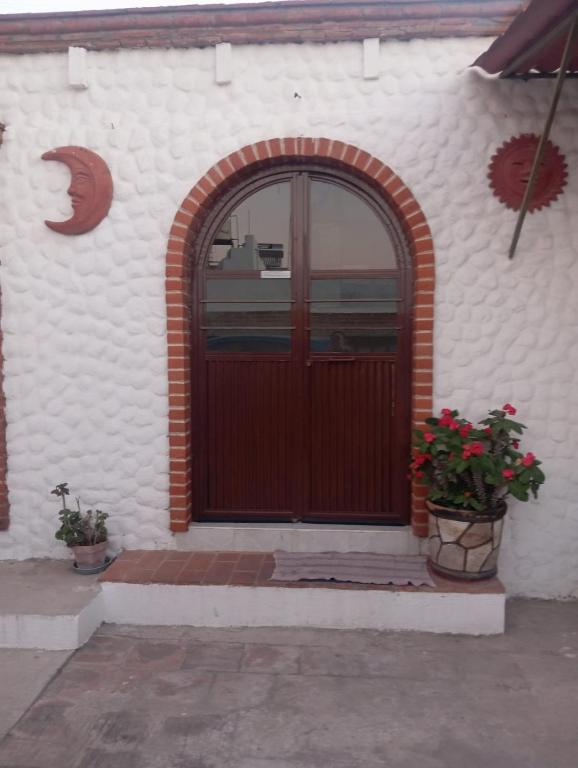 a red door on a white building with two potted plants at Los Malvones in Tequisquiapan