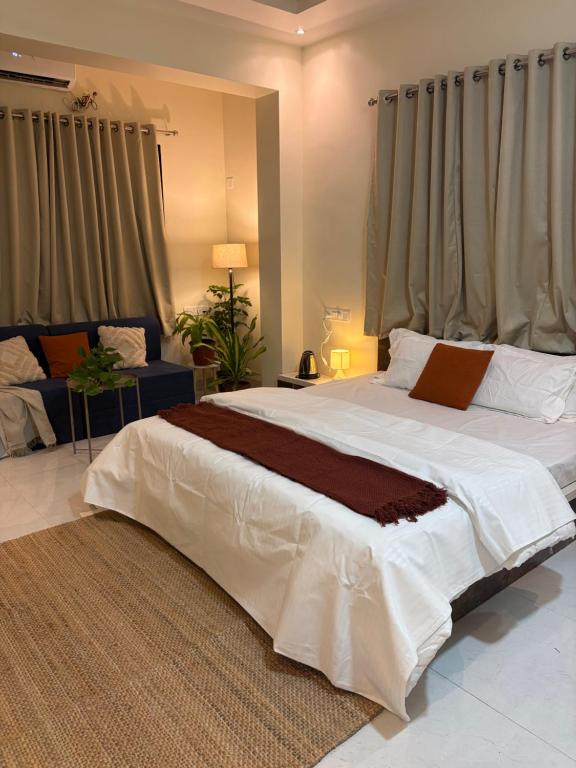 a large white bed in a room with curtains at The Sora Stay in Alibaug
