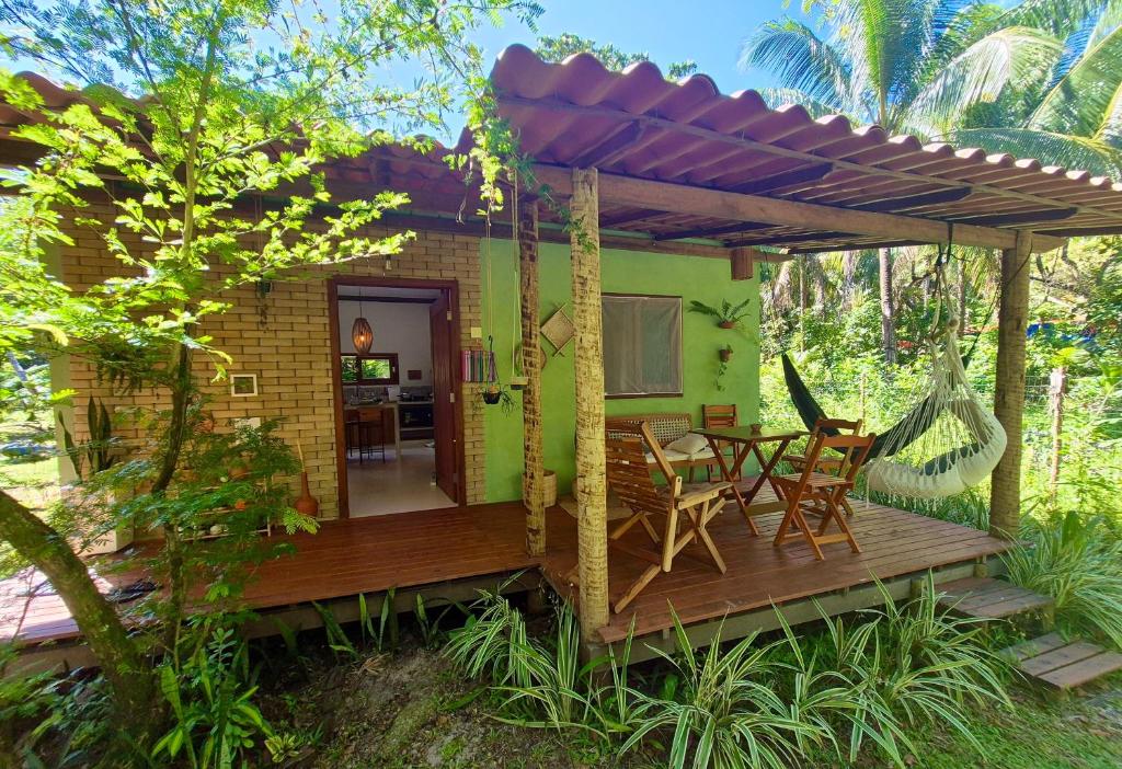 a small house with a deck with a table and chairs at Casa Raiz 1 Moreré - A 3min da praia in Moreré