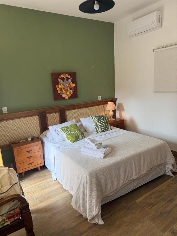 a bedroom with a bed with a green wall at Pousada Vó Iris - Tiradentes Mg in Tiradentes