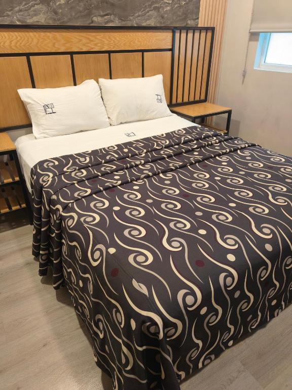 a large bed with a black and white comforter at Hotel Torreon in Mexico City