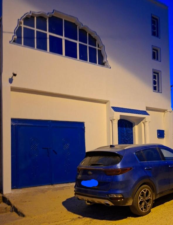 a blue car parked in front of a building at Maison yassine in Douz