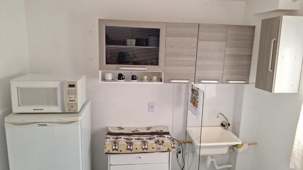 a small kitchen with a microwave and a refrigerator at Bélgica in Presidente Prudente
