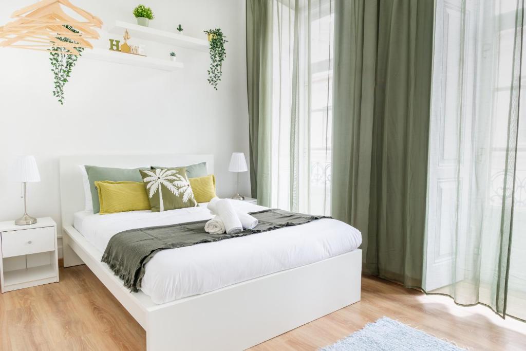 a bedroom with a white bed with green curtains at Bica Palace - Residence in Center of Lisbon in Lisbon