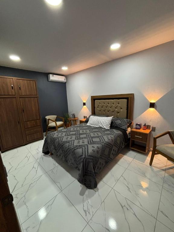 a bedroom with a bed and a couch and chairs at Hotel Casa FRALO in Atotonilco el Alto