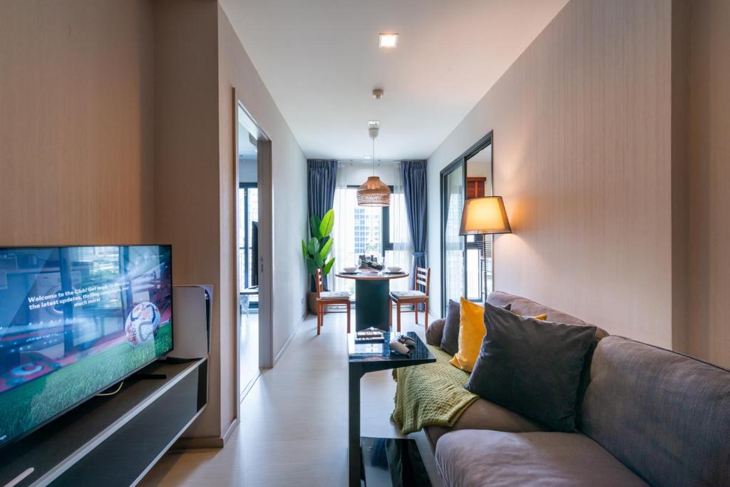 a living room with a couch and a flat screen tv at Upscale Apartment With Train Access Bts Thonglor in Bangkok