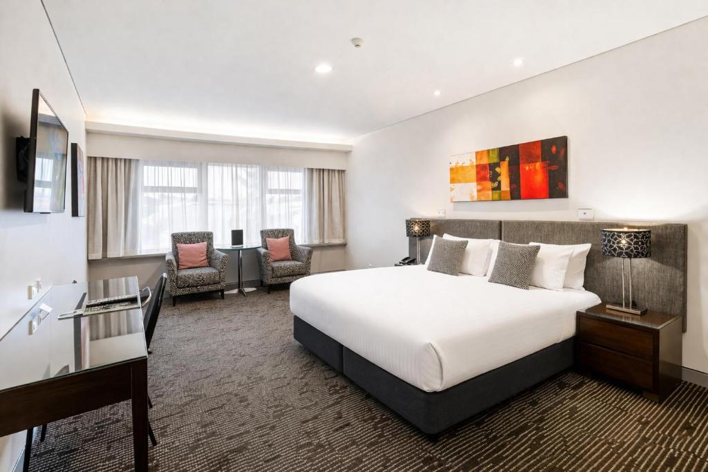 a hotel room with a large bed and chairs at The Colmslie Hotel in Brisbane