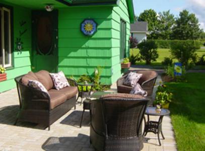 eine Terrasse mit 2 Stühlen und ein grünes Haus in der Unterkunft Suncatcher B&B in Truro