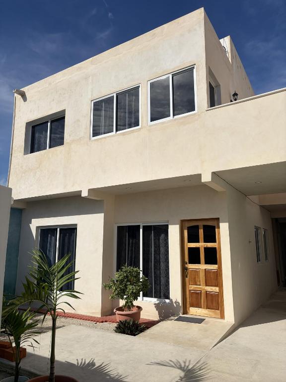 a large white house with a wooden door at Departamento Arena- Oasis del Mar in Progreso