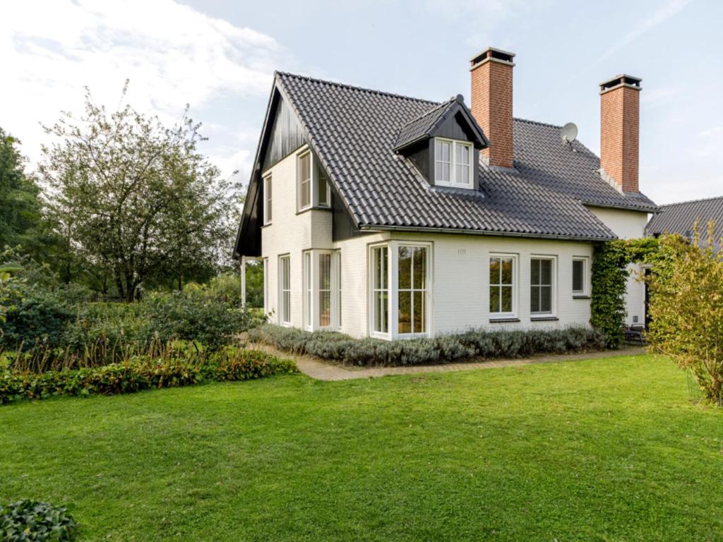 a white house with a black roof and a yard at Achterhoek Estate with Private Pool in Aalten