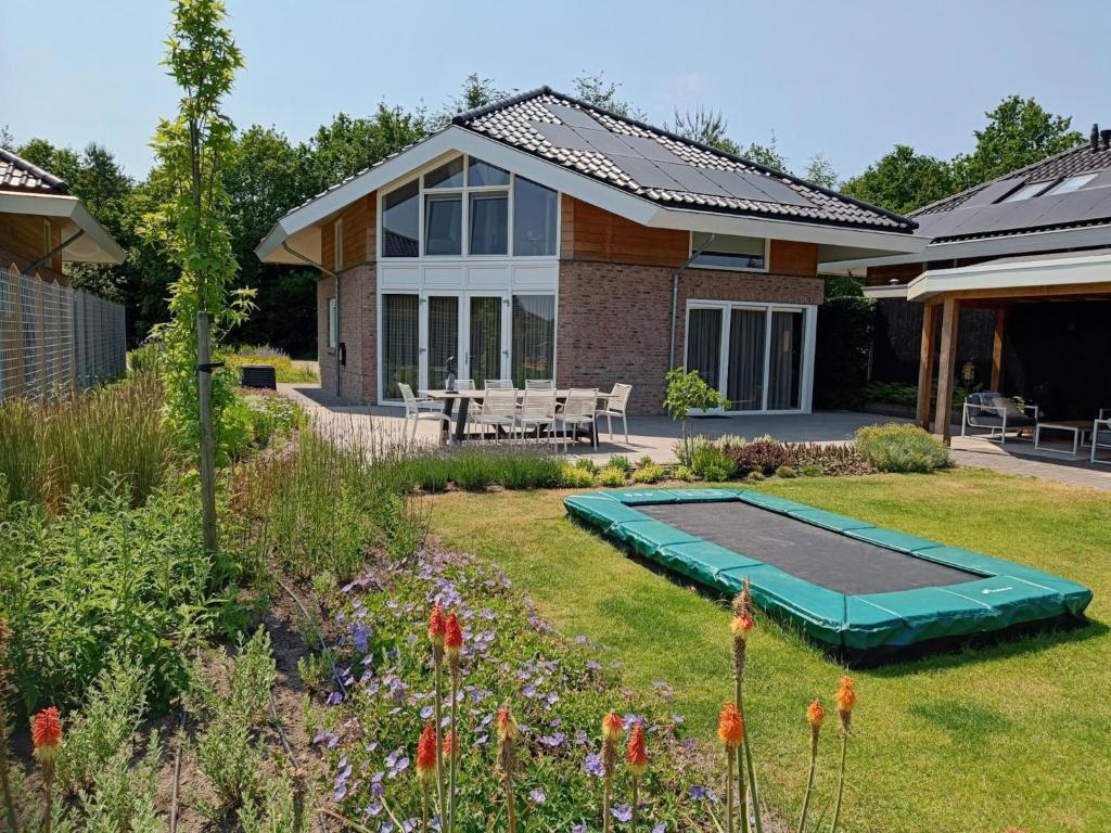 a backyard with a swimming pool and a house at Water Villa, Sauna & Beach in Sibculo